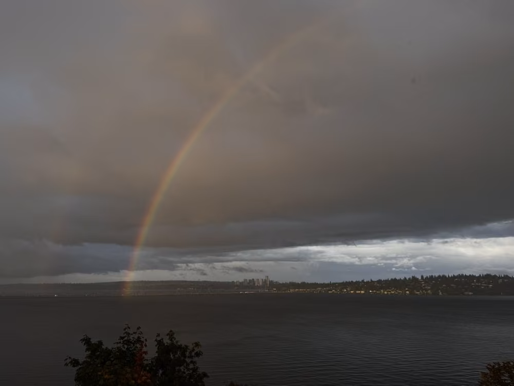 A rainbow over the water beneath storm clouds