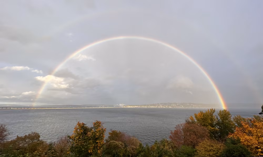 A full rainbow arching over the water